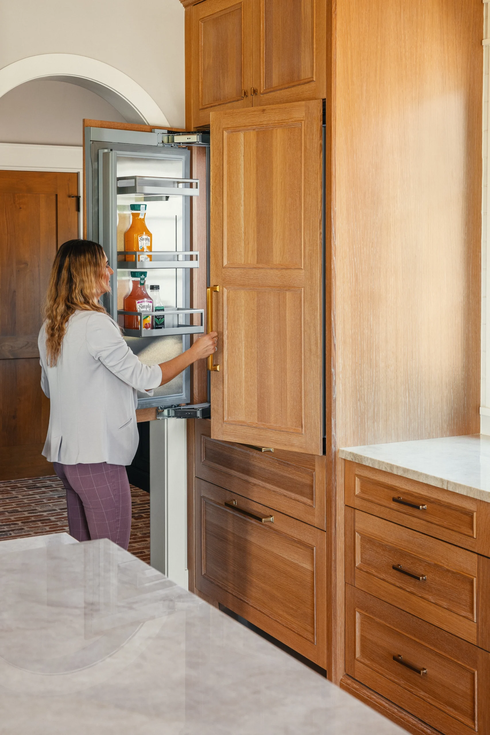 Beautifully remodeled kitchen with a large island featuring a sleek stove with maple blend cabinets in the Laramie door style, painted in the neutral shade of Prairie Dove.