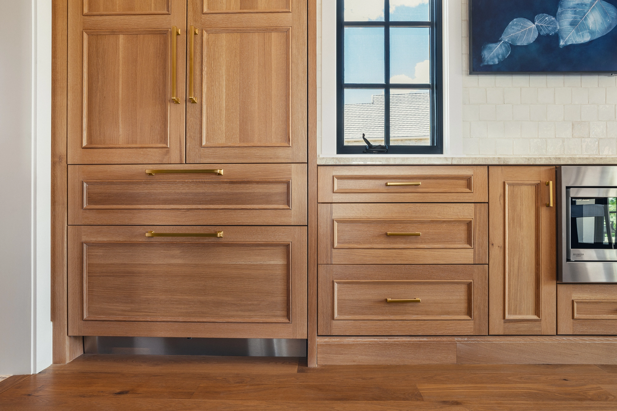 Beautifully remodeled kitchen with a large island featuring a sleek stove with maple blend cabinets in the Laramie door style, painted in the neutral shade of Prairie Dove.
